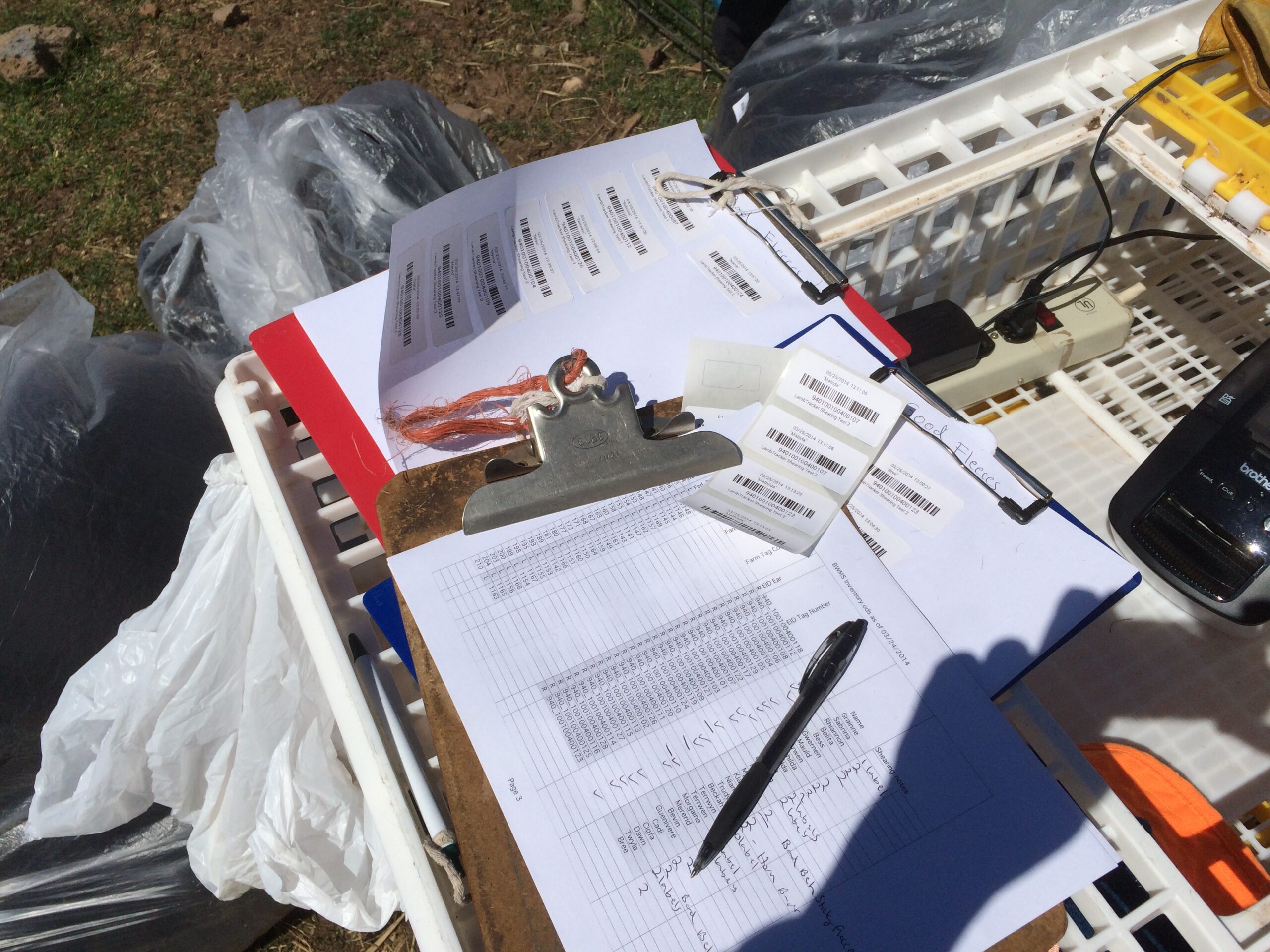 A spreadsheet, barcode labels, and more papers attached to clipboards sit on a temporary work station.