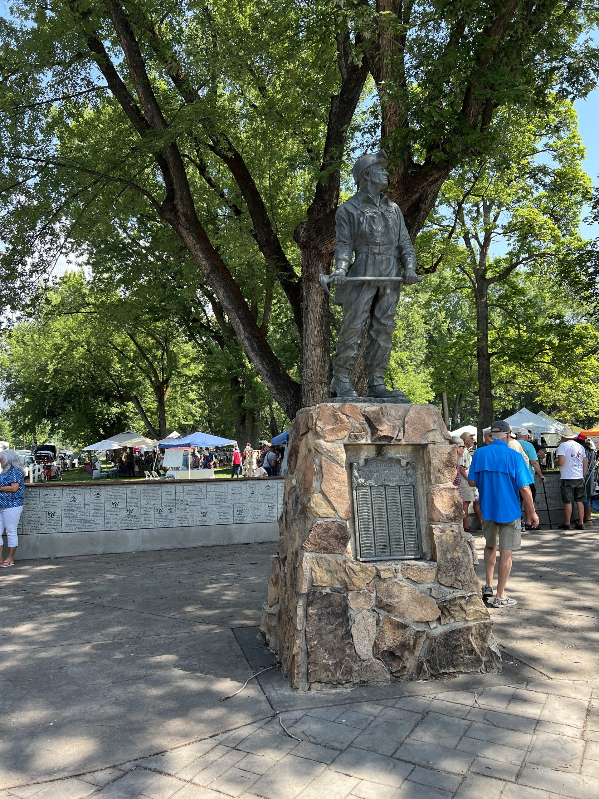 Tents are set up in a park behind a memorial statue. 
